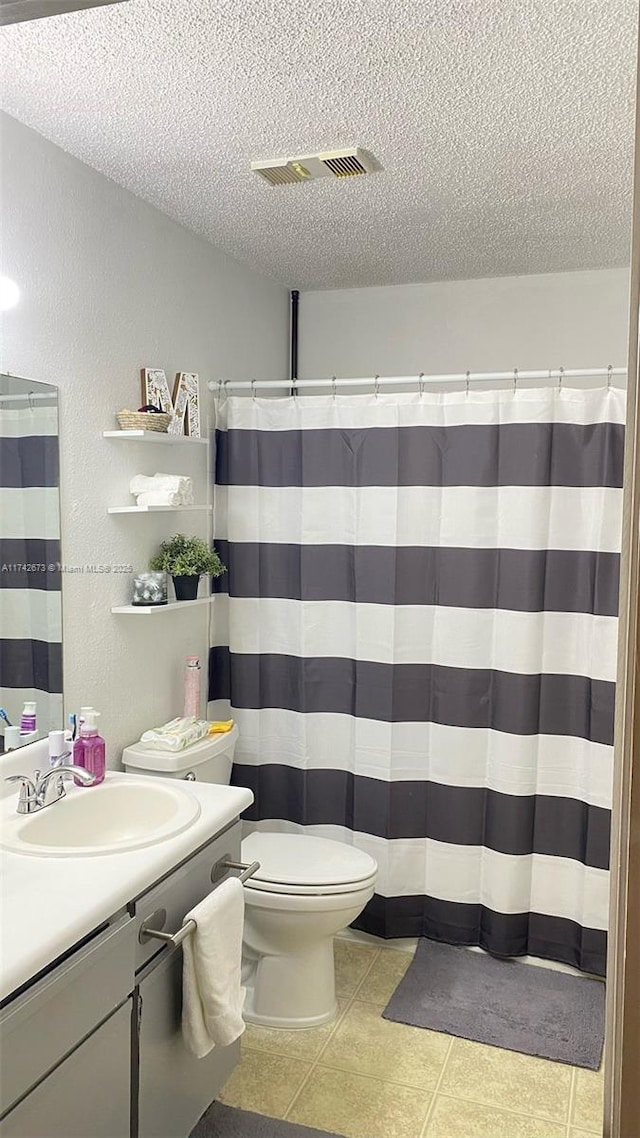 bathroom featuring toilet, a shower with curtain, a textured ceiling, vanity, and tile patterned flooring