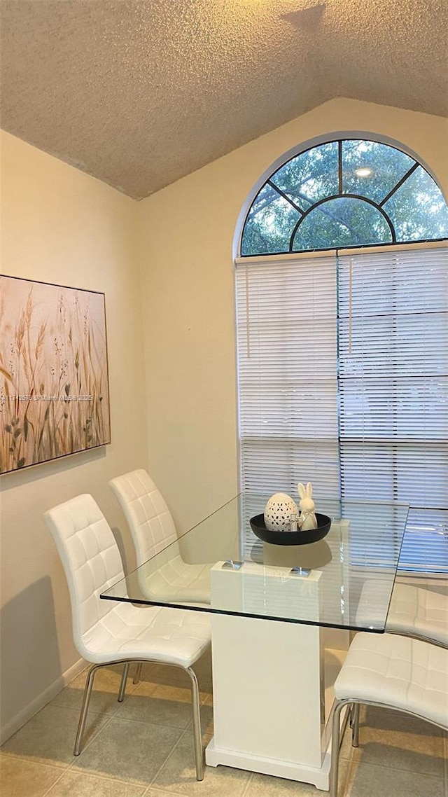 dining area with lofted ceiling, a wealth of natural light, a textured ceiling, and light tile patterned floors