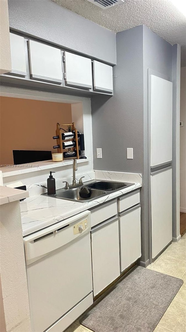 kitchen featuring white cabinetry, dishwasher, sink, and a textured ceiling