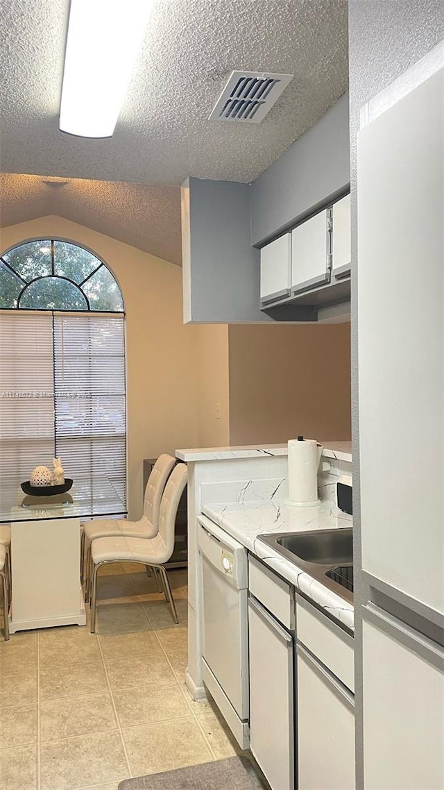 kitchen with white cabinets, a textured ceiling, dishwasher, and light tile patterned flooring