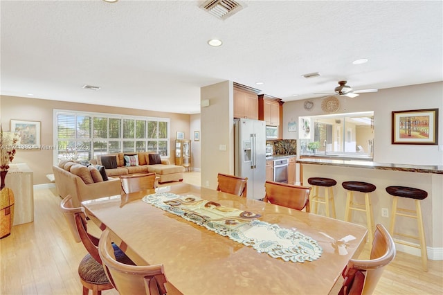 dining space featuring ceiling fan, a textured ceiling, and light hardwood / wood-style floors