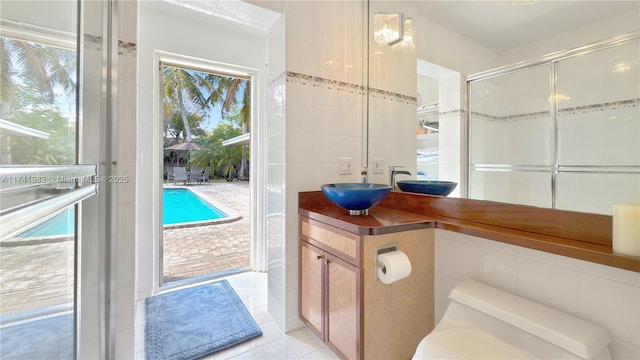 bathroom featuring tile patterned flooring, tile walls, vanity, an enclosed shower, and toilet