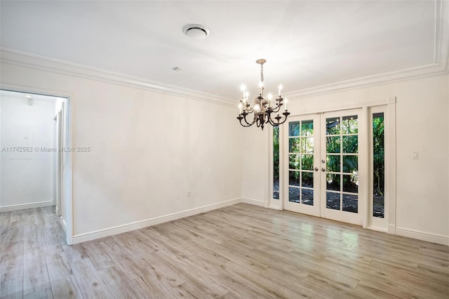 empty room with a notable chandelier, light hardwood / wood-style flooring, ornamental molding, and french doors