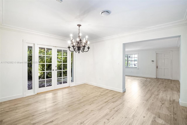 unfurnished room featuring a notable chandelier, crown molding, french doors, and light wood-type flooring