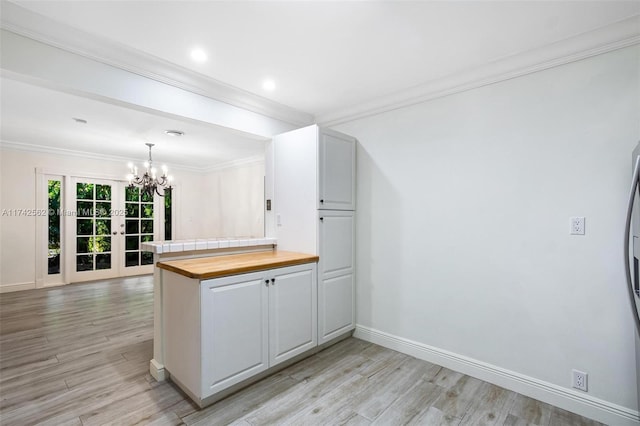 kitchen with wooden counters, hanging light fixtures, ornamental molding, kitchen peninsula, and light wood-type flooring