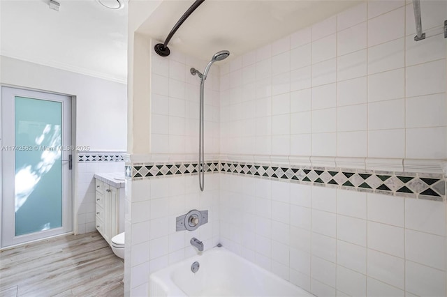 full bathroom with hardwood / wood-style floors, tile walls, tiled shower / bath combo, vanity, and toilet