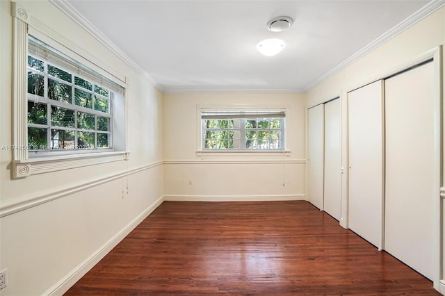 unfurnished bedroom with crown molding, dark hardwood / wood-style floors, and two closets