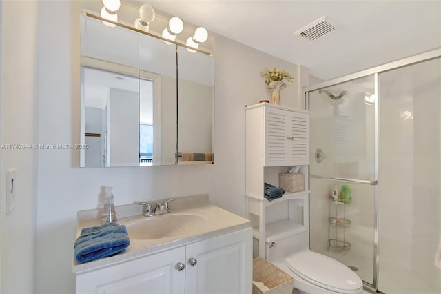 bathroom featuring vanity, a shower with door, and toilet