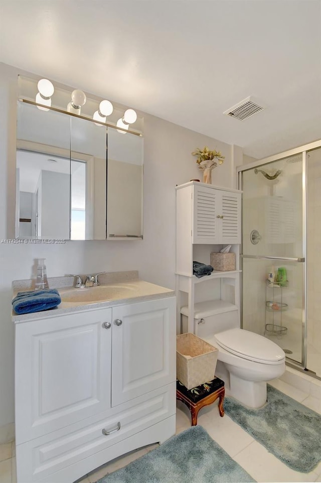 bathroom featuring vanity, toilet, tile patterned floors, and a shower with shower door