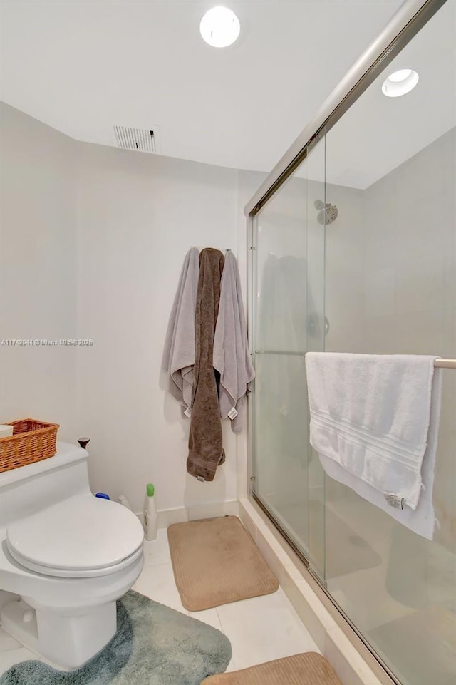 bathroom featuring tile patterned flooring, a shower with shower door, and toilet