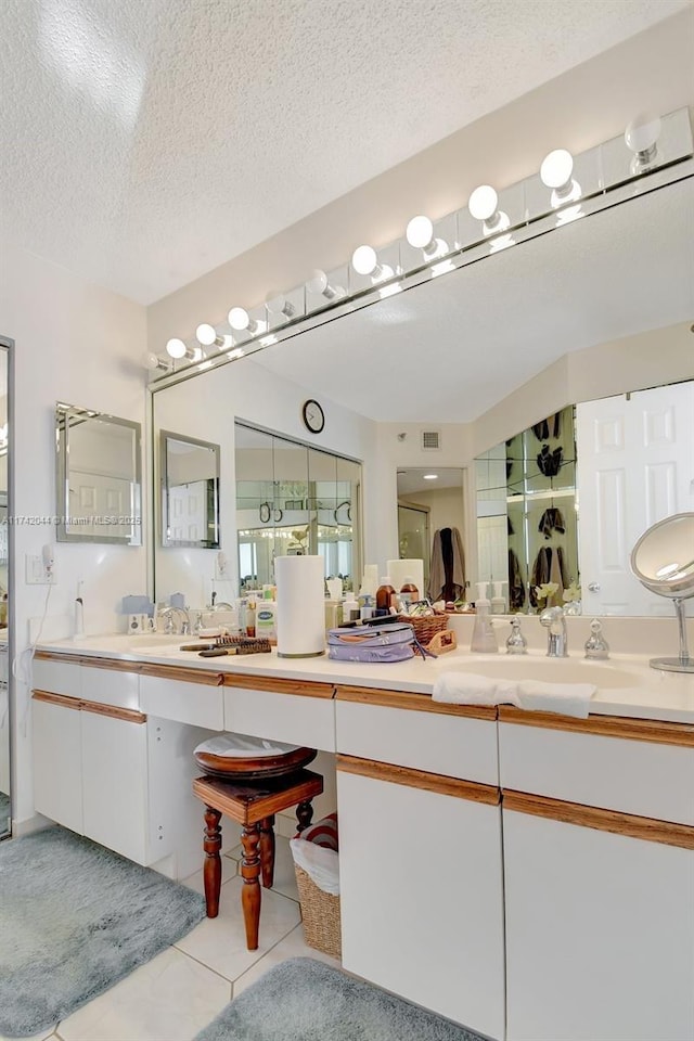 bathroom with tile patterned flooring, vanity, and a textured ceiling