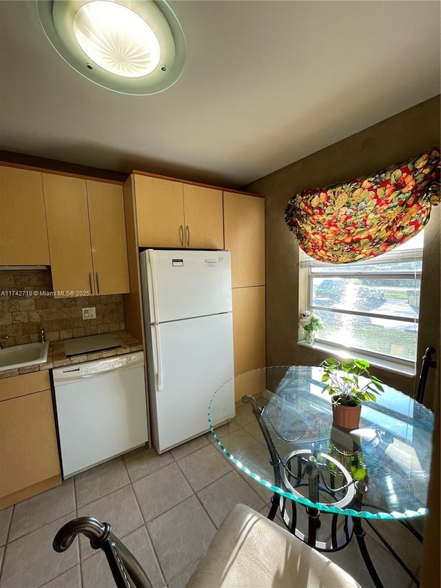 kitchen featuring sink, light tile patterned floors, light brown cabinets, white appliances, and backsplash