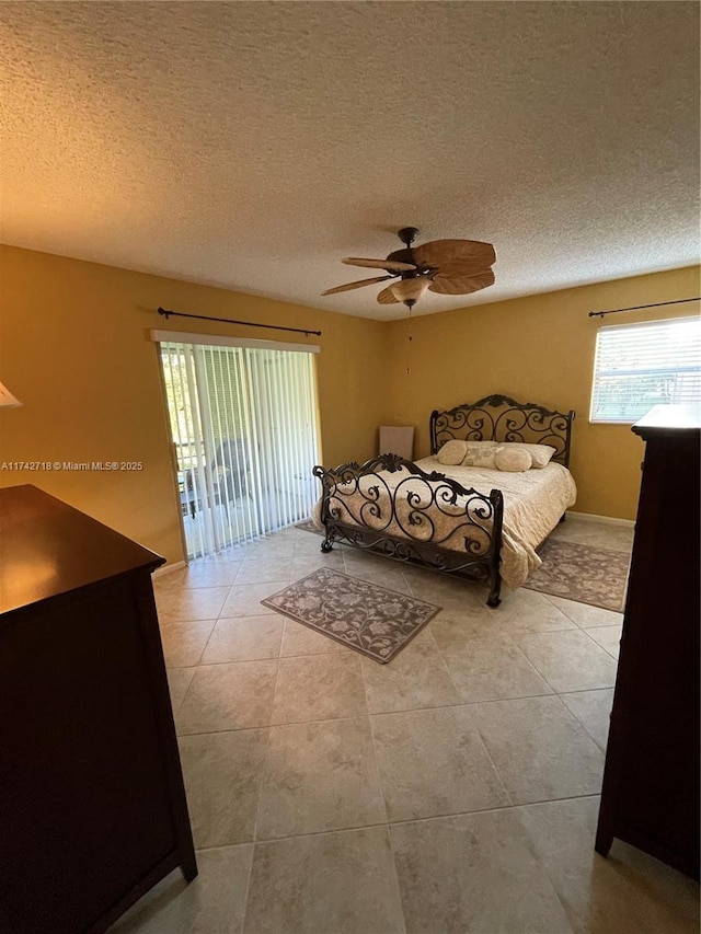 bedroom with ceiling fan, access to outside, a textured ceiling, and light tile patterned flooring