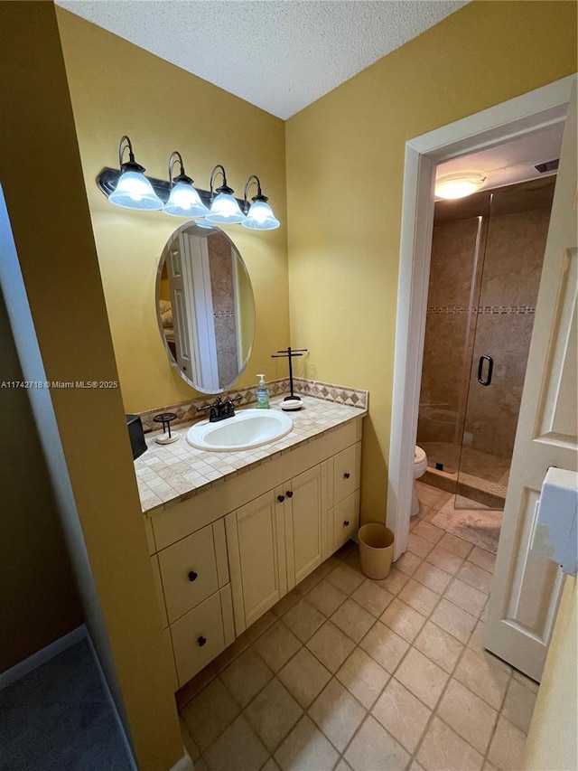 bathroom with vanity, a textured ceiling, a shower with shower door, tile patterned floors, and toilet