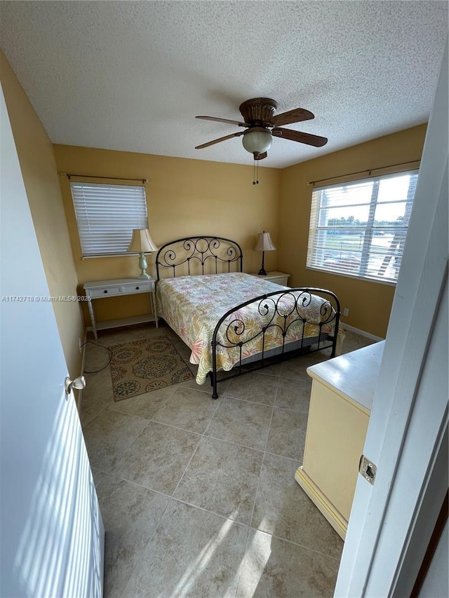 tiled bedroom featuring ceiling fan and a textured ceiling