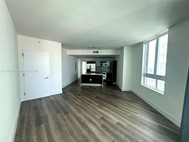 unfurnished living room with dark hardwood / wood-style flooring and a textured ceiling