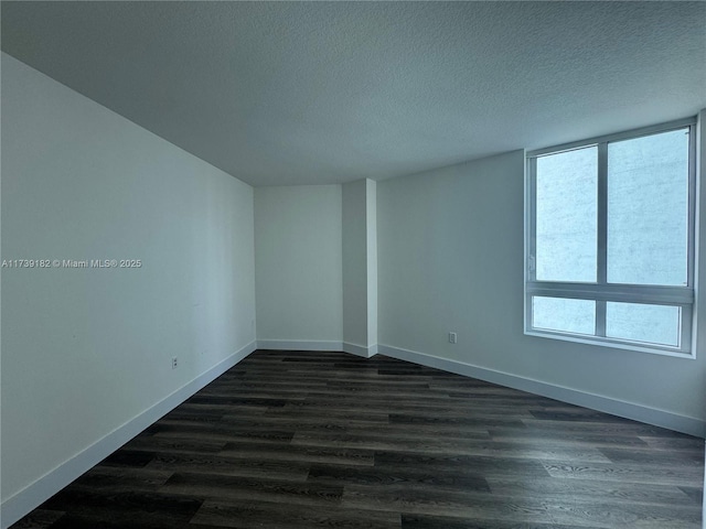 spare room with dark hardwood / wood-style floors and a textured ceiling