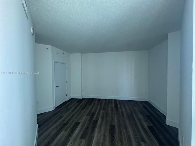 spare room with dark hardwood / wood-style floors and a textured ceiling