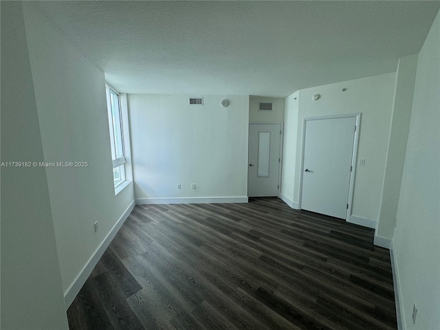 unfurnished room with dark wood-type flooring and a textured ceiling