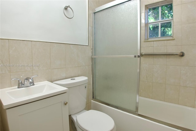 full bathroom with vanity, toilet, combined bath / shower with glass door, and tile walls