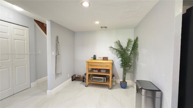 interior space featuring visible vents, marble finish floor, a textured ceiling, recessed lighting, and baseboards