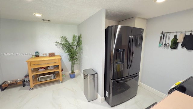 kitchen featuring a textured ceiling, baseboards, visible vents, and black fridge