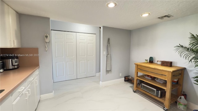 interior space featuring visible vents, baseboards, recessed lighting, marble finish floor, and a textured ceiling