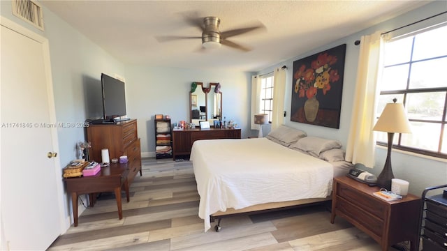 bedroom with light wood-type flooring, visible vents, and ceiling fan