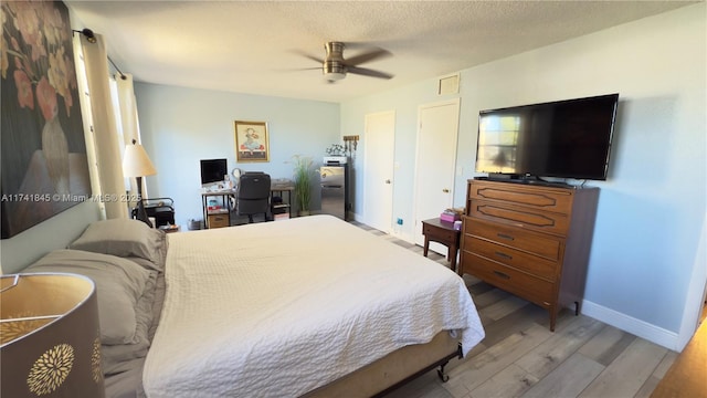 bedroom featuring visible vents, baseboards, wood finished floors, a textured ceiling, and a ceiling fan