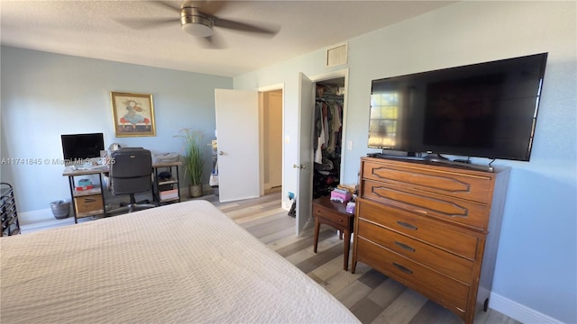 bedroom with light wood finished floors, visible vents, baseboards, a closet, and a ceiling fan