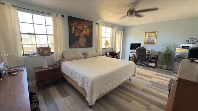 bedroom with a ceiling fan, light wood-type flooring, and baseboards