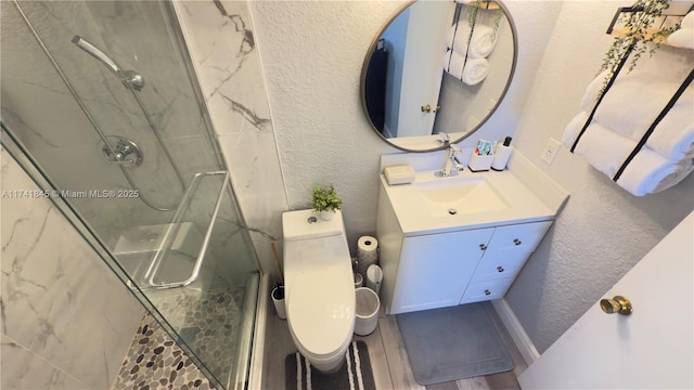 full bathroom featuring toilet, wood finished floors, a marble finish shower, vanity, and a textured wall