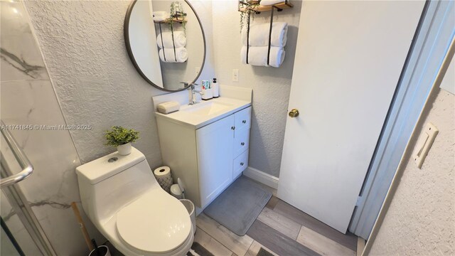 bathroom with vanity, wood finished floors, toilet, and a textured wall