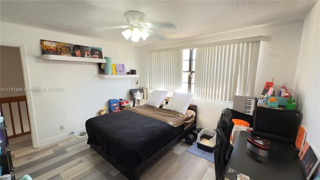 bedroom featuring ceiling fan, wood finished floors, baseboards, and a textured ceiling