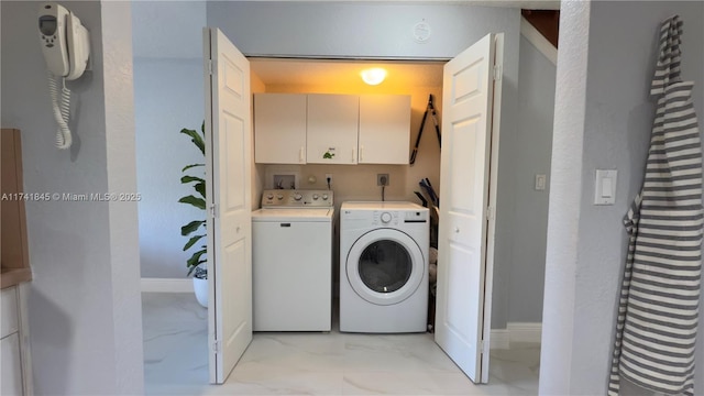 clothes washing area with baseboards, cabinet space, marble finish floor, and washing machine and clothes dryer