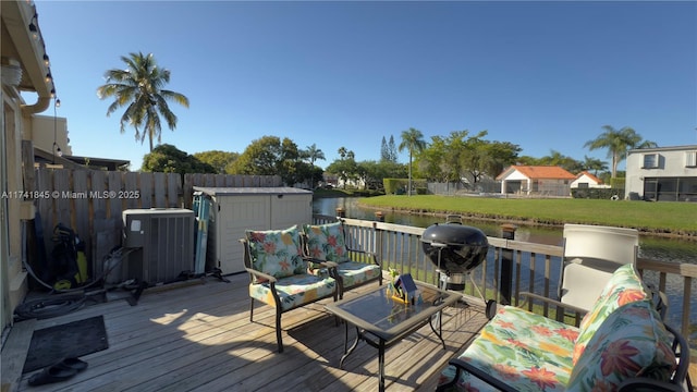 deck featuring a water view, area for grilling, central AC, a storage shed, and an outdoor structure