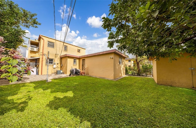 back of property with central AC and a lawn