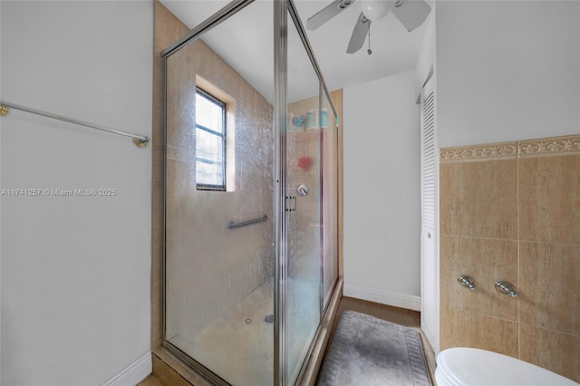 bathroom featuring toilet, tile walls, ceiling fan, and a shower with shower door