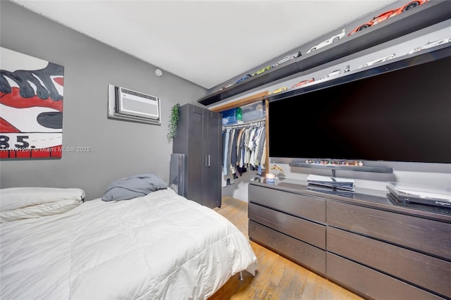 bedroom with a closet, an AC wall unit, and light wood-type flooring