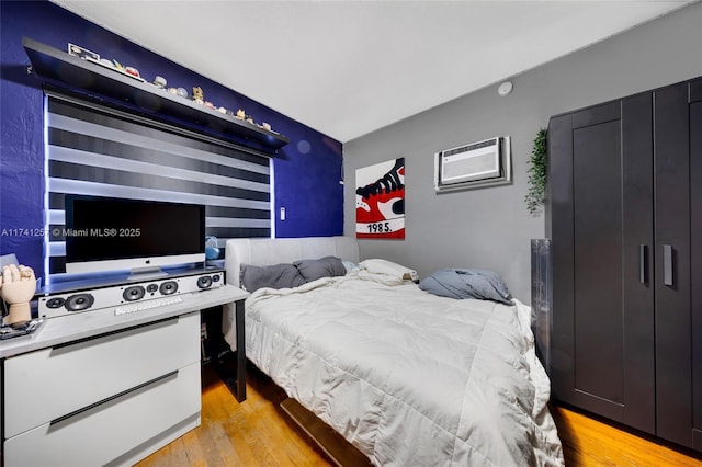 bedroom with an AC wall unit and light wood-type flooring