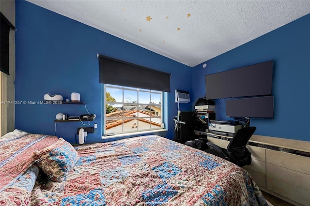 bedroom with lofted ceiling, a wall mounted AC, and a textured ceiling