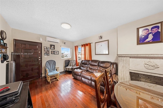 living room with a wall mounted air conditioner, dark hardwood / wood-style floors, and a textured ceiling