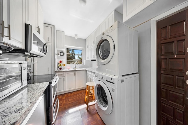 laundry area featuring stacked washer / drying machine, dark parquet flooring, and sink