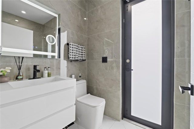 bathroom with vanity, tile walls, and toilet