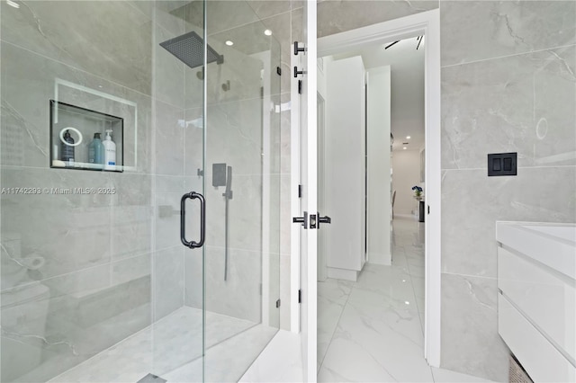 bathroom with tile walls, vanity, and a shower with door