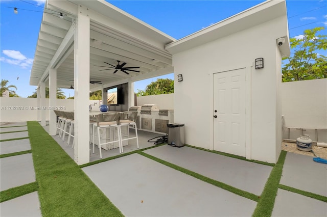 view of patio / terrace featuring grilling area, an outdoor bar, ceiling fan, and an outdoor kitchen