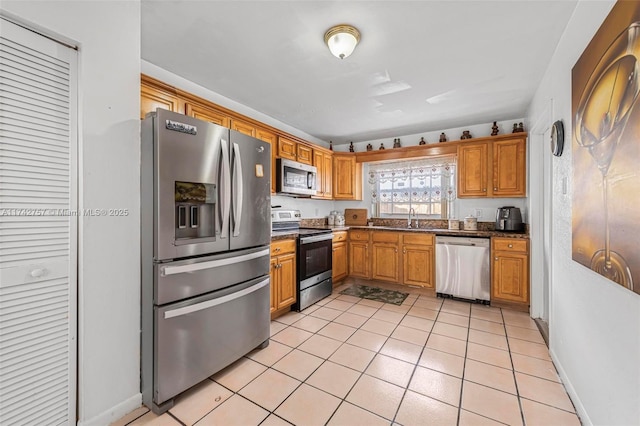 kitchen featuring appliances with stainless steel finishes, sink, dark stone counters, and light tile patterned floors