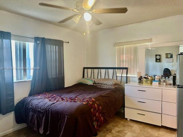 bedroom featuring multiple windows, ceiling fan, and a textured ceiling