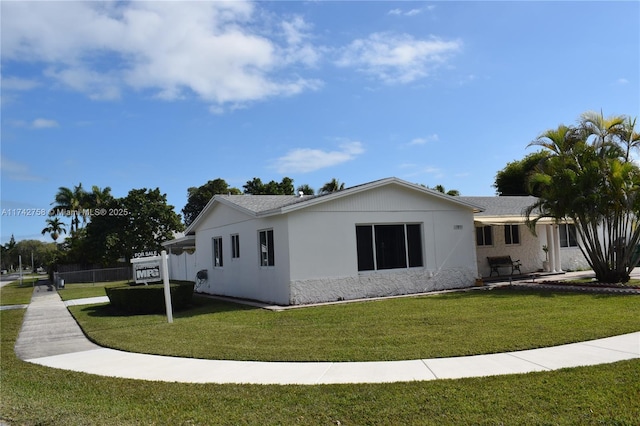 view of home's exterior with a lawn, fence, and stucco siding