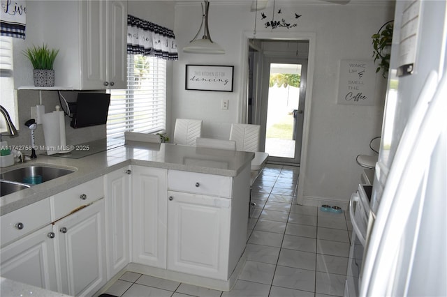 kitchen featuring baseboards, a peninsula, a sink, light countertops, and white cabinets